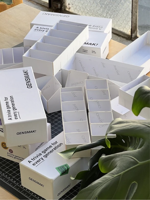 Early GENSMAK! game boxes being packed by hand